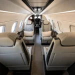 Салон Embraer Phenom 300E со светлыми креслами и центральным проходом